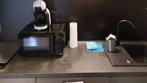 Eine Küche mit Mikrowelle, Kaffeemaschine und Spüle.