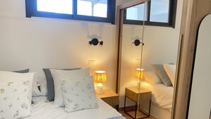 Un dormitorio con una cama grande, dos mesitas de noche con lámparas, un espejo y una ventana.