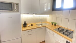 Una cocina moderna con armarios blancos, un microondas de acero inoxidable, un fregadero, una cafetera y un lavavajillas.