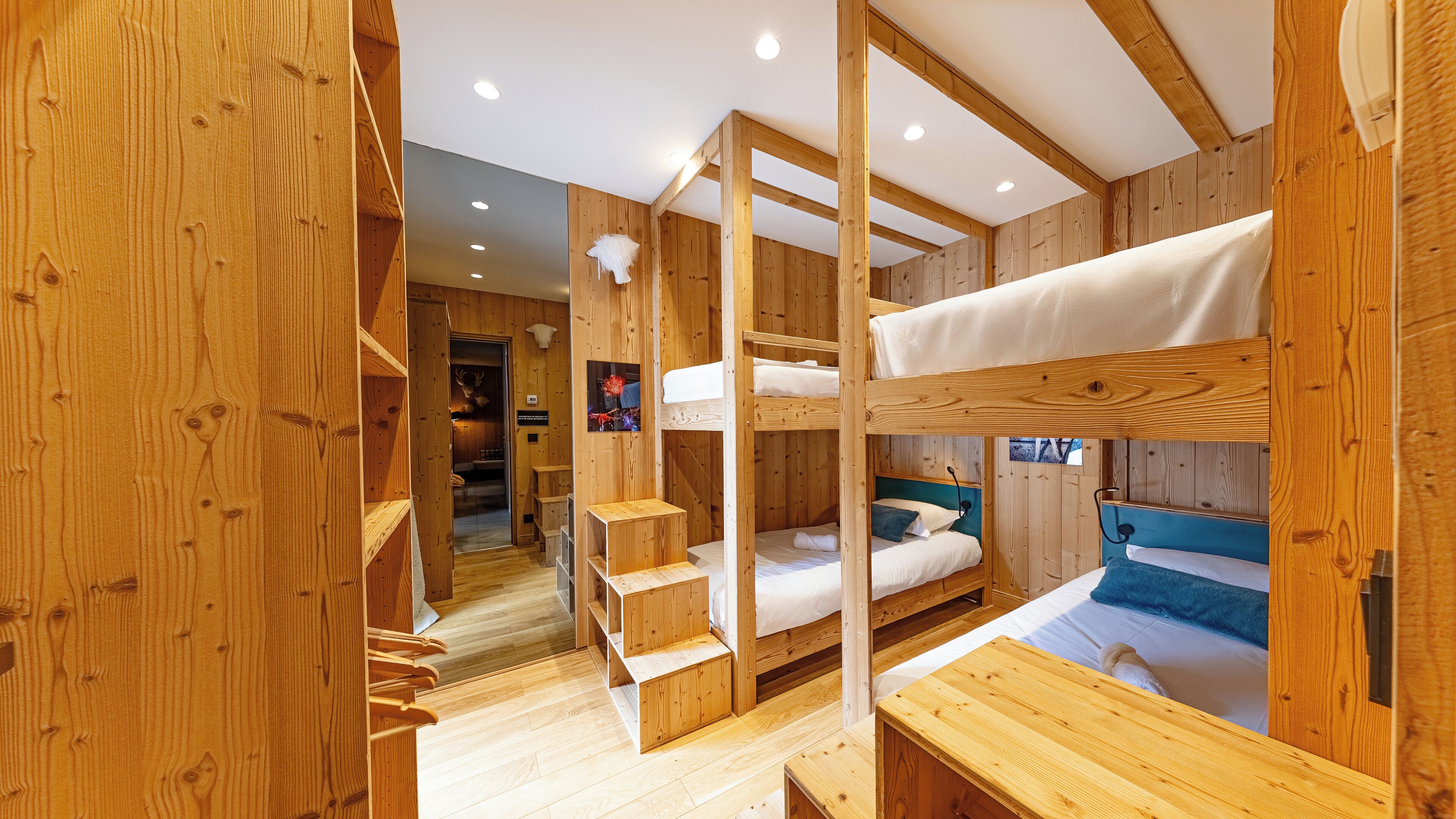 Ein Holzblockhaus-Innenraum mit Etagenbetten, einer Holztreppe und einem kleinen Tisch.