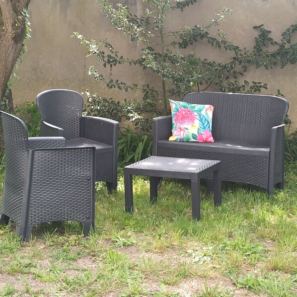An outdoor seating area with wicker furniture and a colorful cushion.