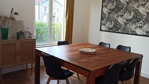En matplats med ett träbord, svarta stolar, en karta och en växt.