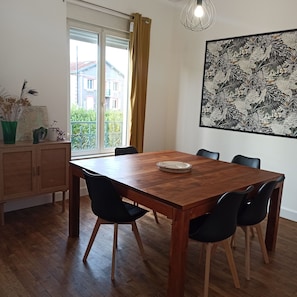 A dining area with a wooden table, black chairs, a map, and a plant.