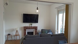 Ett modernt vardagsrum med en öppen spis, en stor TV som är monterad på väggen och en matplats med ett träbord och stolar.