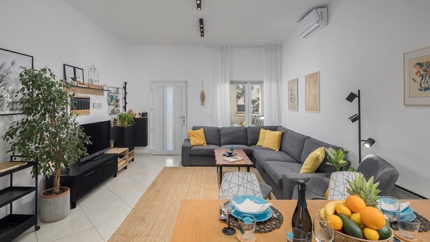 A modern living room with a grey sofa, a coffee table, and a dining area with a fruit bowl and plates. - House Runa in Porec, Croatia (Porec)