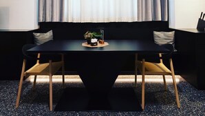 A modern dining area with a black table, wooden chairs, a black sofa, and a small plant on the table. - Pepper Suite (Bolzano)