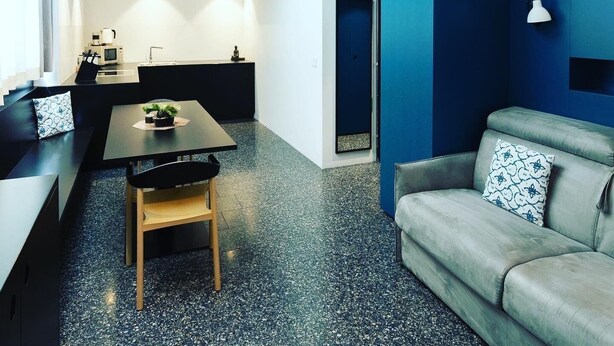 A modern apartment with a dining area, a sofa, and a staircase leading to an upper level. - Pepper Suite (Bolzano)