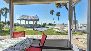 A room with a large window overlooking a pool area, outdoor seating, and a gazebo.