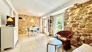 A cozy room with a stone wall, a dining area with a table and chairs, a wicker chair, and a bed. - Pet-Friendly Holiday Home Lara with Pool and Sea view - excellent choice for a relaxing family getaway (Brzac)