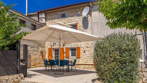A stone building with a patio area featuring outdoor furniture and a large umbrella.