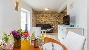 A dining area with a stone wall, a sofa, a TV, and a white cabinet.