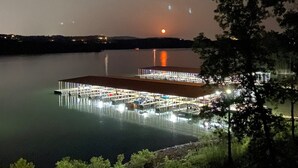 Imóvel à beira-mar com um cais, área coberta com assentos e uma grande extensão de água refletindo luzes.