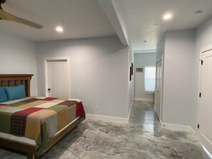 Un dormitorio con una cama, un ventilador de techo y un pasillo que lleva a otra habitación.