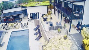 Un edificio moderno con piscina, mobiliario exterior y un elemento decorativo de piedra.