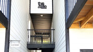 Um edifício com uma placa com a frase 'this is the life' e uma placa com a inscrição 'lavanderia' à esquerda.