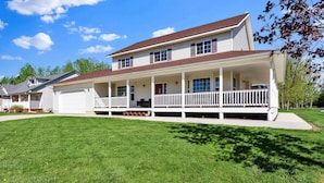 A two-story house with a front porch and a garage. - Moose Caboose Hot Tub + Schweitzer Views (Bonner County)