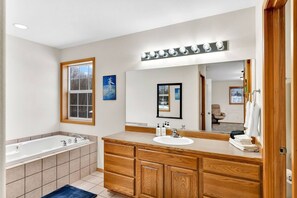 Een moderne badkamer met een groot bad, een dubbele wastafel en een grote spiegel.