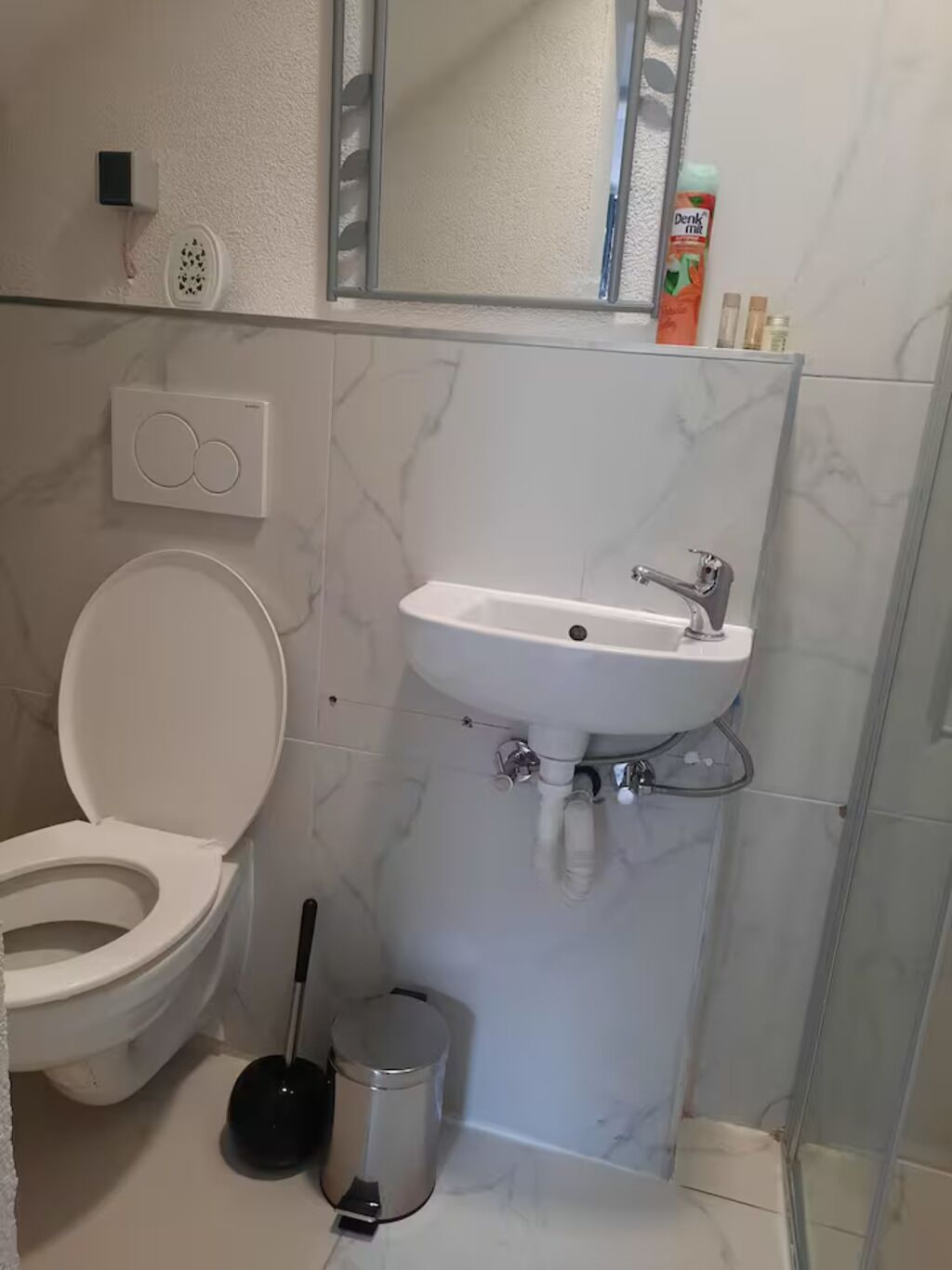 Un baño con inodoro, lavamanos y espejo.
