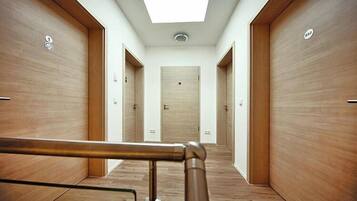A hallway with wooden doors, a skylight, and a metal handrail.