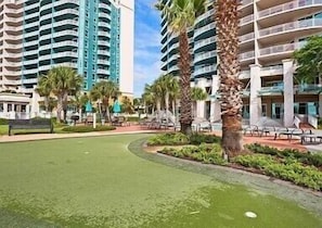 Un resort con edificios altos, palmeras y un césped bien cuidado.
