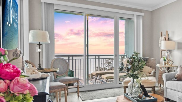 Ein geräumiges Wohnzimmer mit grauem Sofa, einem Couchtisch und Blick auf den Balkon.