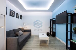 Een moderne woonkamer met een grijze bank, een witte salontafel en een zwarte tv-kast.