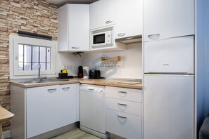 A compact kitchen with a built-in microwave, a coffee maker, and a toaster.
