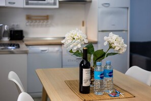 A kitchen with a dining table set with a bottle of wine, two water bottles, and white flowers.