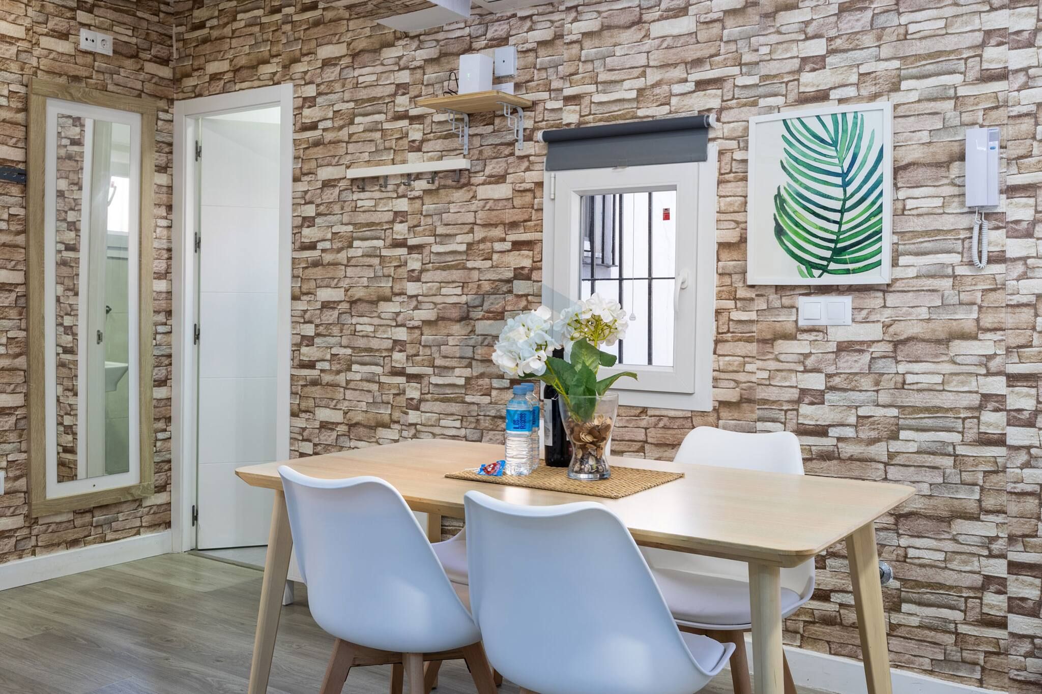 Un coin repas avec un mur en pierre, une fenêtre offrant une vue agréable et une table entourée de chaises.