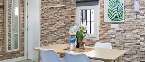 A dining area with a stone wall, a window with a view, and a table with chairs.