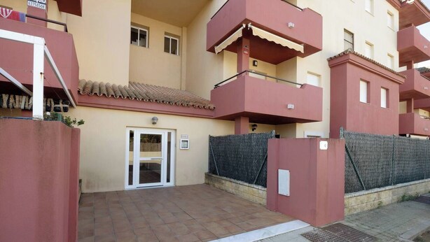 A residential building with a gated entrance, a tiled patio, and a balcony.