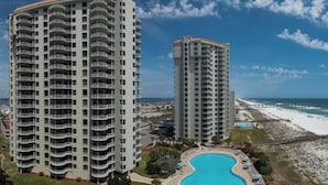 Two high-rise buildings with balconies, a swimming pool, and a beach view.