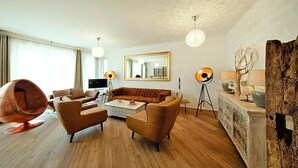 Una sala moderna con un sofá, sillones, una mesita de centro y una silla con forma de huevo única.