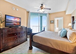 Une chambre à coucher avec un lit, une commode, un téléviseur et un balcon offrant une vue.