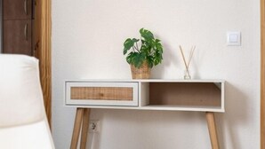 A minimalist room with a white desk, a wicker plant, and a reed diffuser. - Isaac Peral by Staycare (Rota)