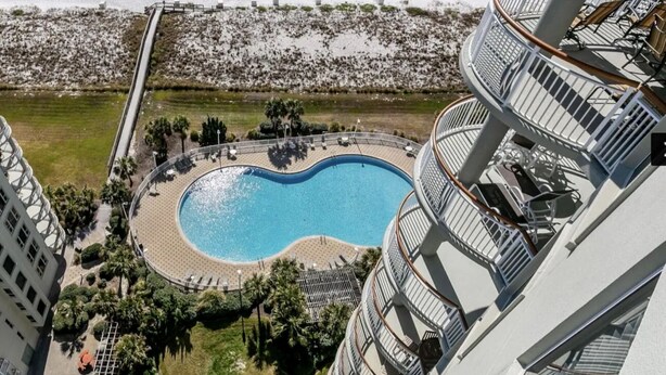 A high-rise building with a rooftop pool, a beach, and a promenade.