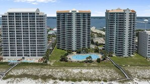 A high-rise hotel with multiple floors, a central courtyard with a swimming pool, and a beach area in the foreground.