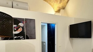 Un vaste espace de vie au design moderne, comprenant un canapé, des œuvres d’art accrochées aux murs et un téléviseur à écran plat fixé au mur.