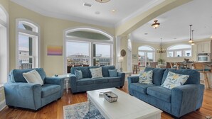 Ein geräumiges Wohnzimmer mit zwei blauen Sofas, einem weißen Couchtisch und einem großen Fenster mit Blick nach draußen.