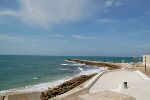 Une promenade en bord de mer, avec un muret de pierre, des bancs et des lampadaires.