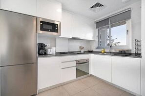Eine moderne Küche mit Edelstahlgeräten, weißen Schränken und einem Fenster, das für natürliches Licht sorgt.