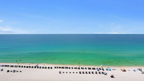A beach with rows of umbrellas and sun loungers. - 12th fl Beachfront 3BR/3BA & Beach Service / Xtra Fridge & Icemaker Sleeps 8 (Navarre Beach)