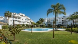 Ein Resort mit weißen Gebäuden, einem Swimmingpool und Palmen.