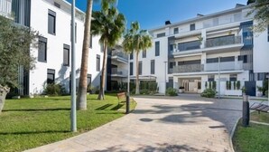 Ein moderner Apartmentkomplex mit Innenhof, Palmen und einem gepflasterten Weg.