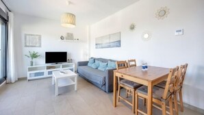 Ein modernes Wohnzimmer mit einer Couch, einem Fernseher, einem Esstisch und Stühlen.