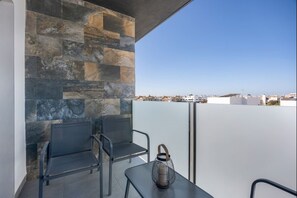 A balcony with stone wall, two chairs, a table, and a lantern. - Nerea Rota free parking by Staycare (Rota)