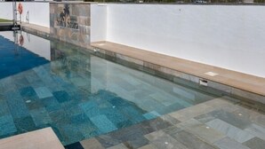 Ein klares Schwimmbecken mit einer Fliesenveranda und einer weißen Wand mit einem Logo.