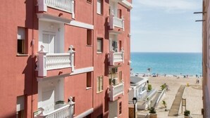 A multi-story hotel with balconies overlooking a beach.