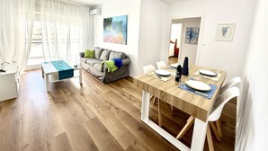 Una sala de estar moderna con un sofá, una mesa de comedor para dos personas y una pequeña mesa de centro.