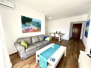 Ein modernes Wohnzimmer mit grauem Sofa, einem Couchtisch und einem Gemälde an der Wand.